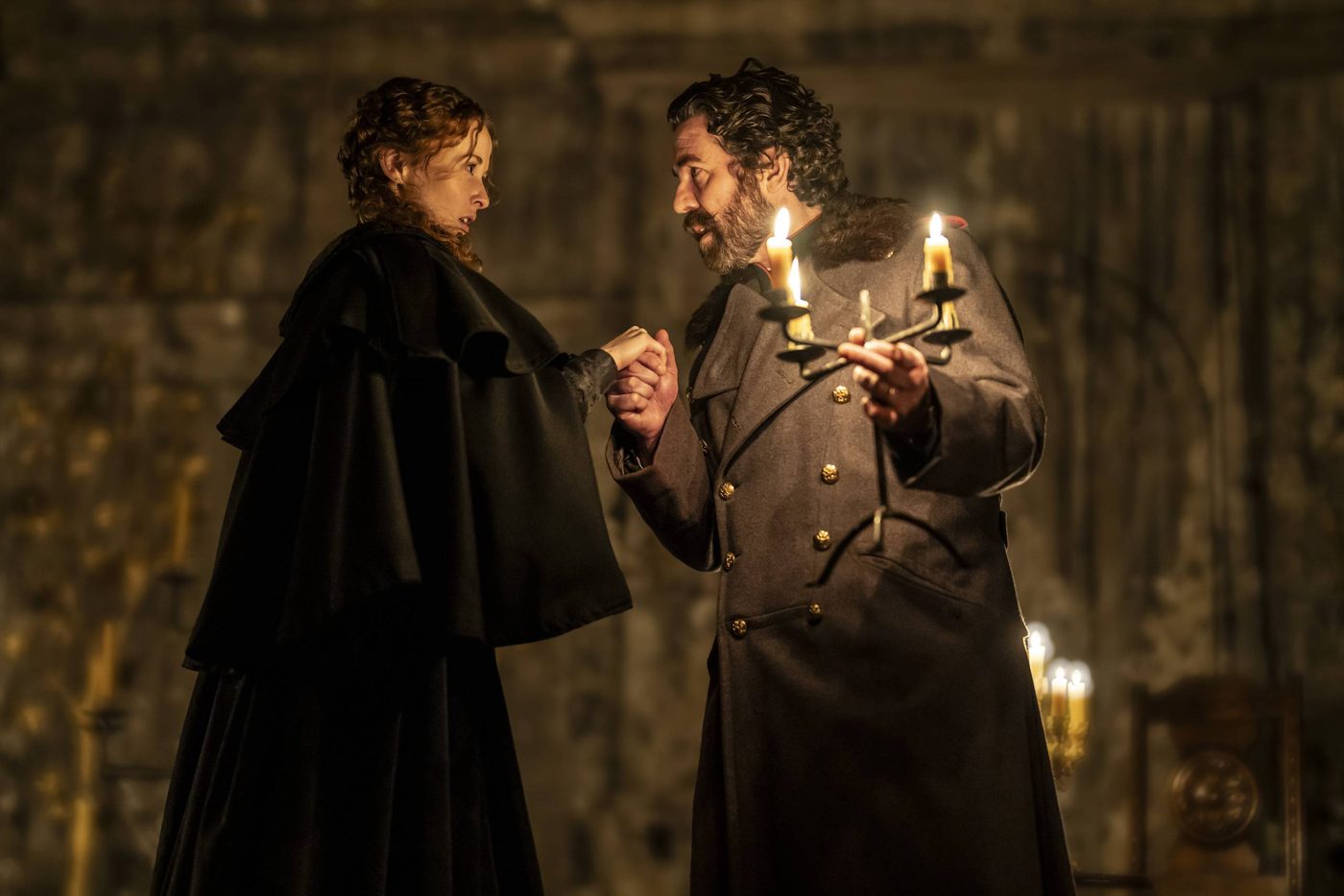 Shannon Tarbet as Masha and Paul Ready as Aleksandr Vershinin in Three Sisters. Photographed by Johan Persson. Shannon Tarbet as Masha and Paul Ready as Aleksandr Vershinin in Three Sisters. Aleksandr has grasped Masha's hand and they are looking intensely at each other. Aleksandr also holds a lit candelabra in his other hand.