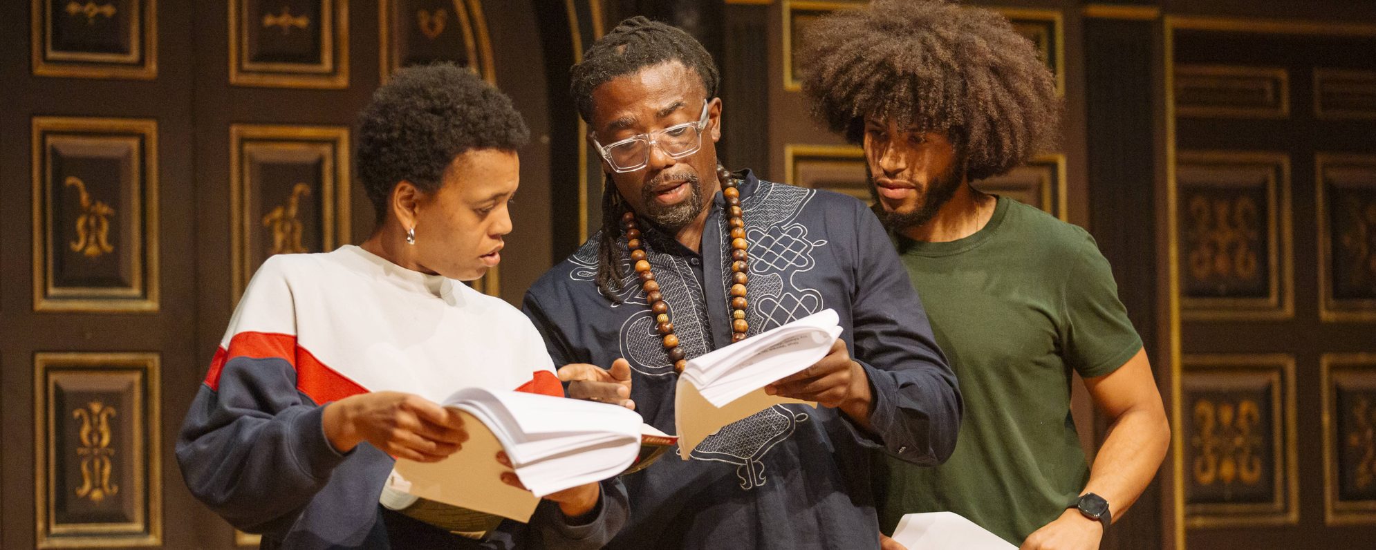 CD_6956_edit-scaled-aspect-ratio-2000-800 Three people examining scripts on stage in the Sam Wanamaker Playhouse.