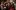 Christmas At The Snow Globe-Shakespeare's Globe-2019-Tristram Kenton A group of people wearing festive hats, scarfs and knit wear, stand together singing carols.