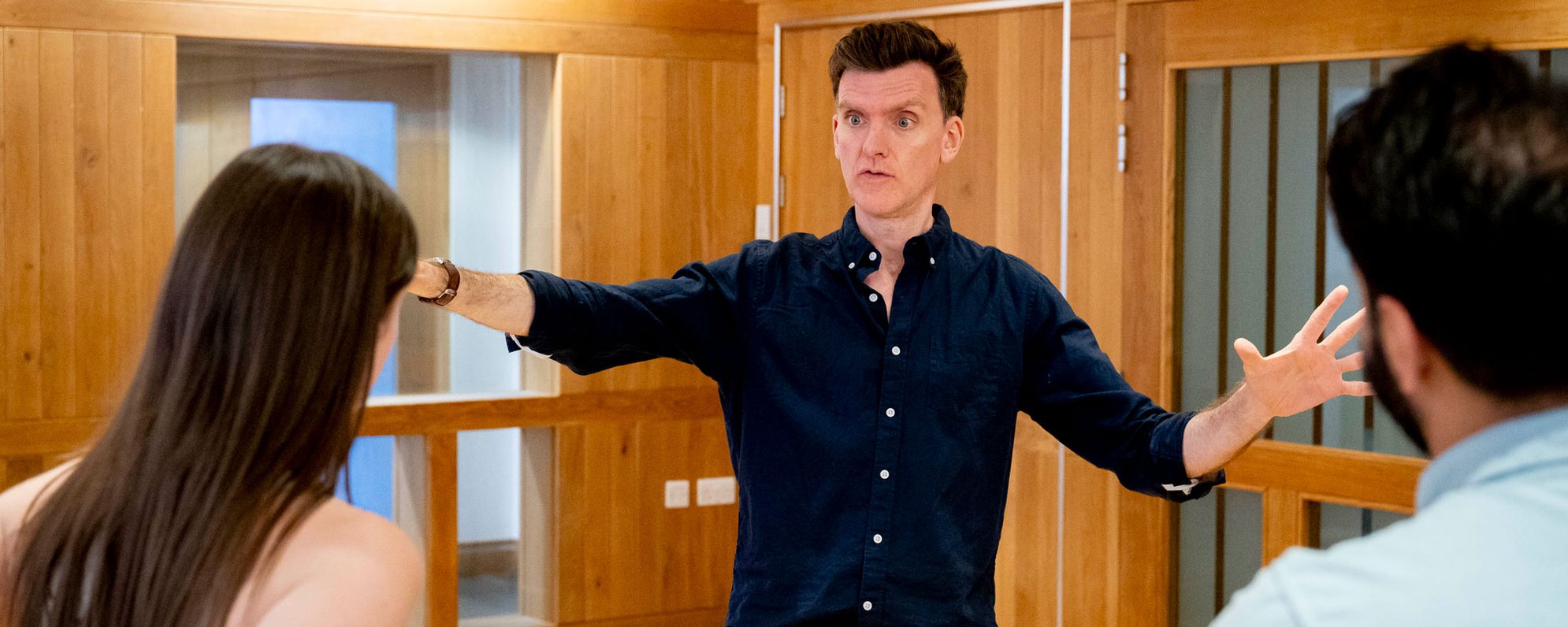 Corporate-Training-2000-x-800 A man in a navy blue shirt delivering training with his arms outstretched enthusiastically