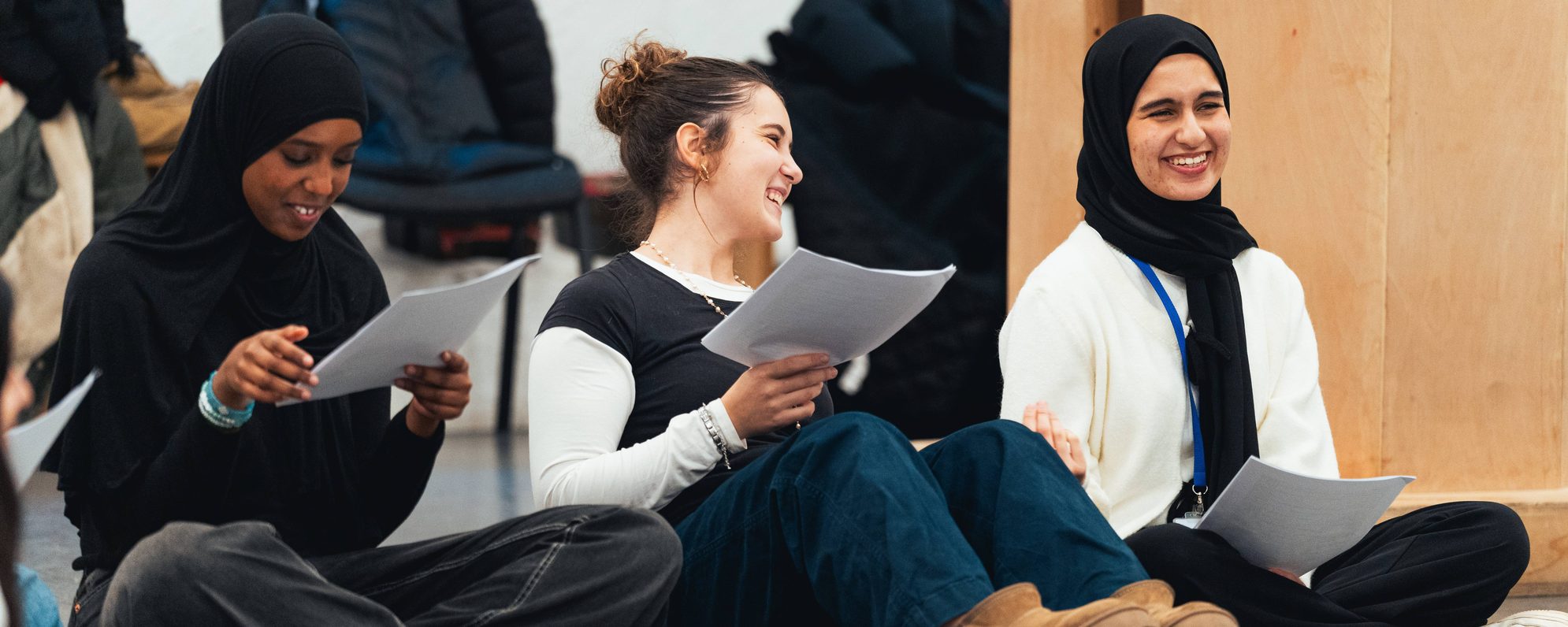 DSC08698-Edit-1-scaled-aspect-ratio-2000-800 Students in a workshop, laughing as they read together from scripts