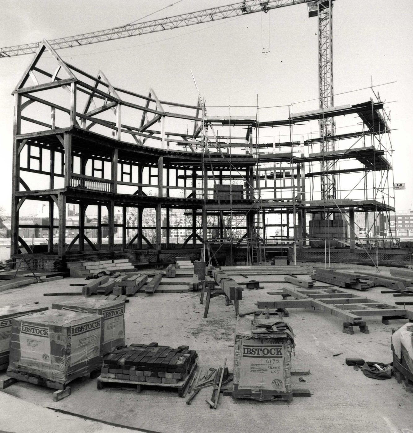 Globe Theatre construction timber with crane A timber circular structure starts to take shape on a construction site, with a crane in the background.