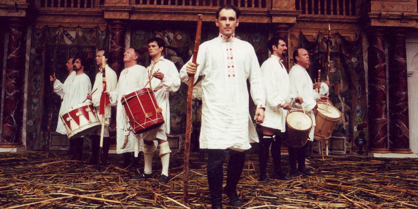 Henry V Globe Theate 1997 Mark Rylance and Company Shakespeare's Globe A group of actors wearing white tunics stand in a v-formation on a stage covered in straw.