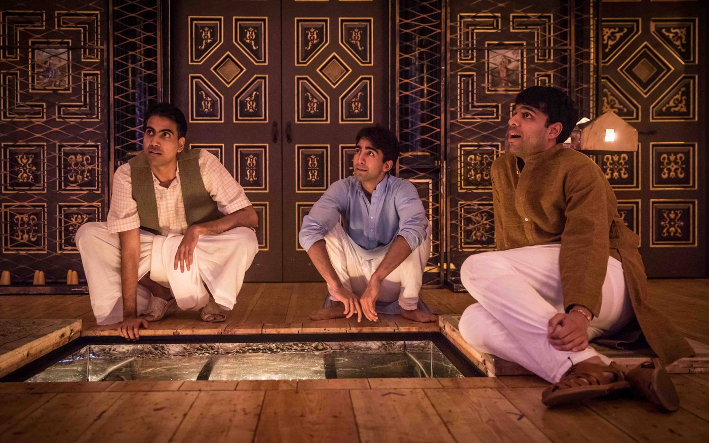 Lions and Tigers PROD-129 Three actors sit around a trap door on a candelit stage.