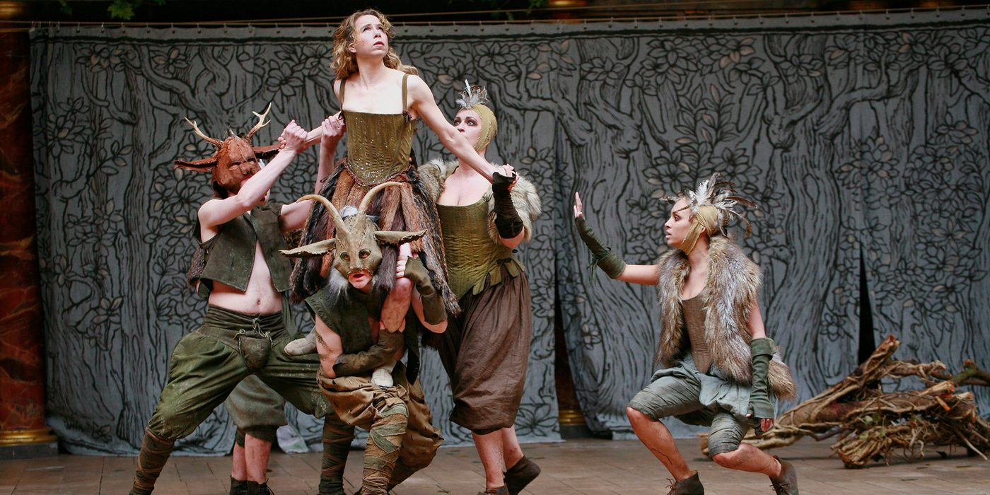 Midsummer's Day YouTube Dream Shakespeare's Globe A woman wearing a green corset dress is lifted into the air by a group of people wearing fur and antlers.