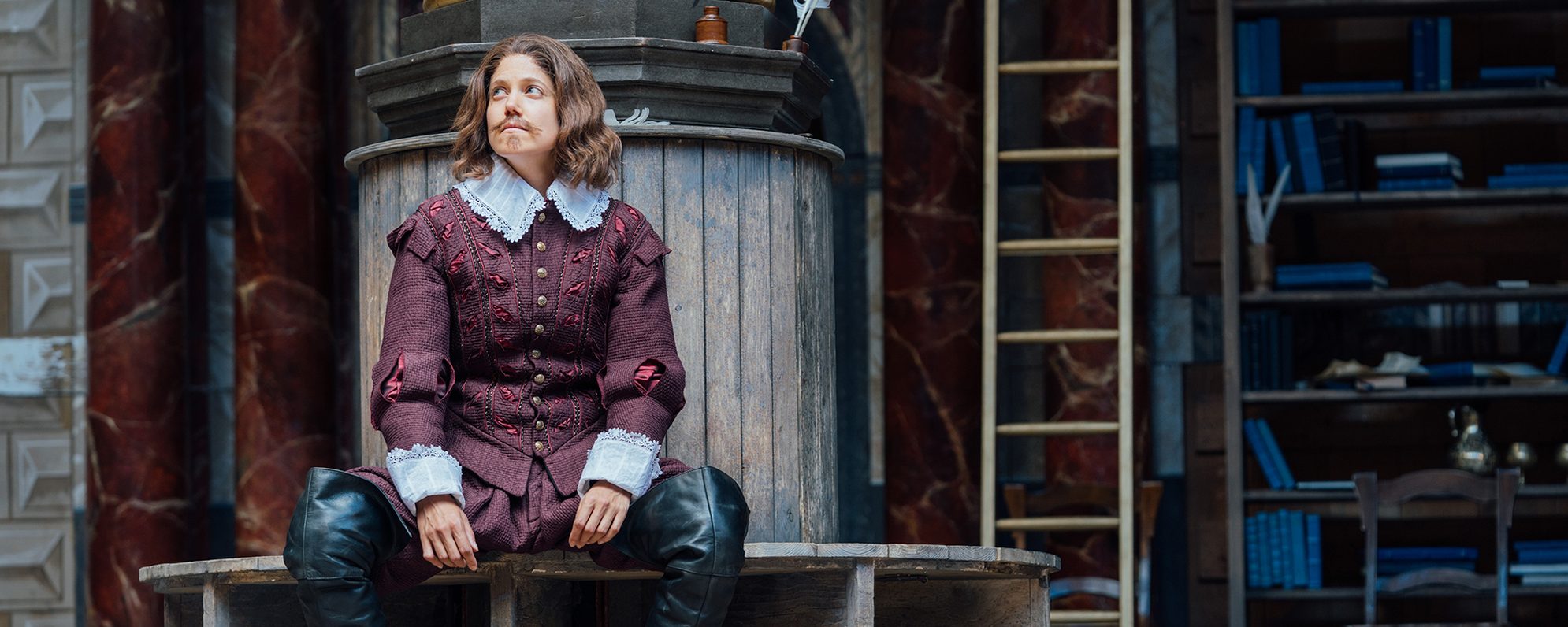 Shakespeare_shakespearesworld_discover_updated_mastheadimage An actor playing William Shakespeare sits by a pillar on the Globe stage