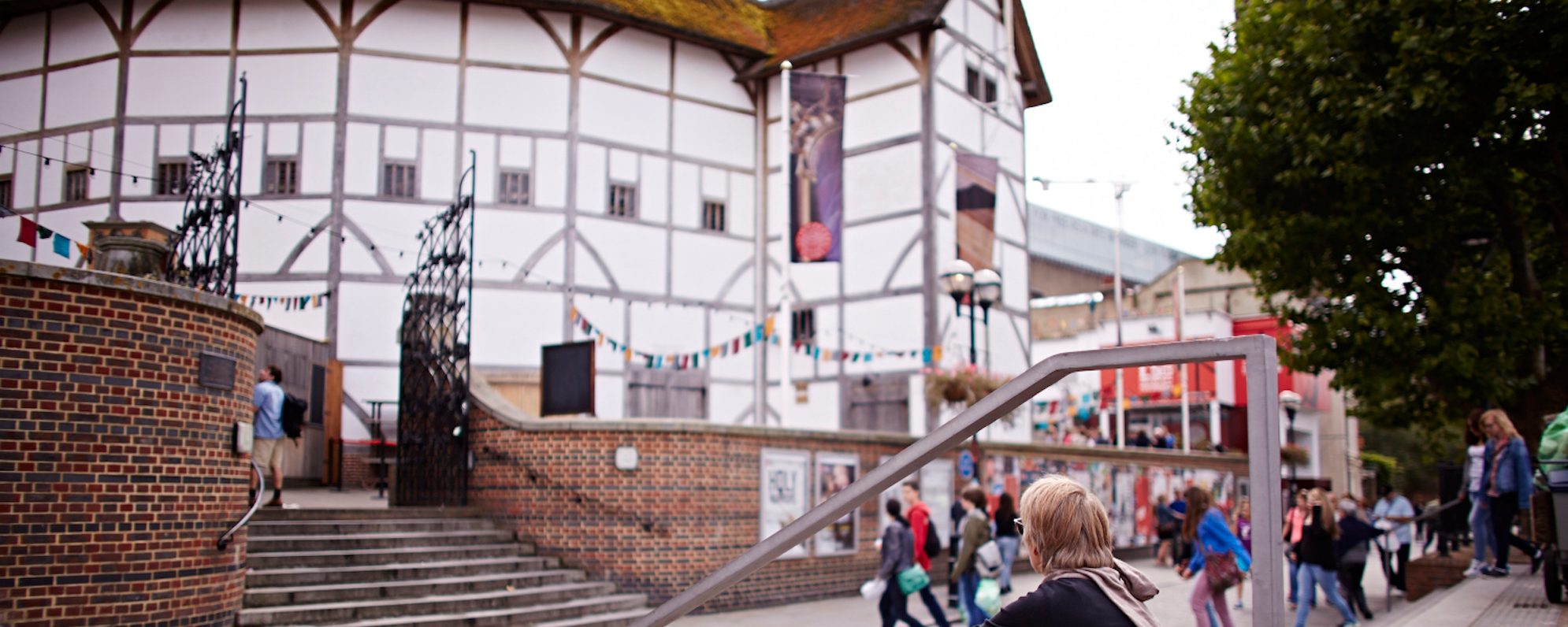 Visit A woman sits outside a white theatre