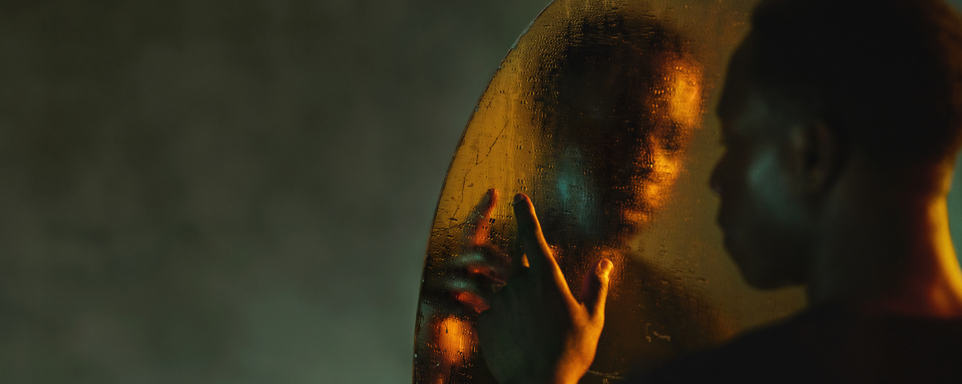 Othello image An actor looking into a mirror. The mirror is covered in water which distorts the reflection