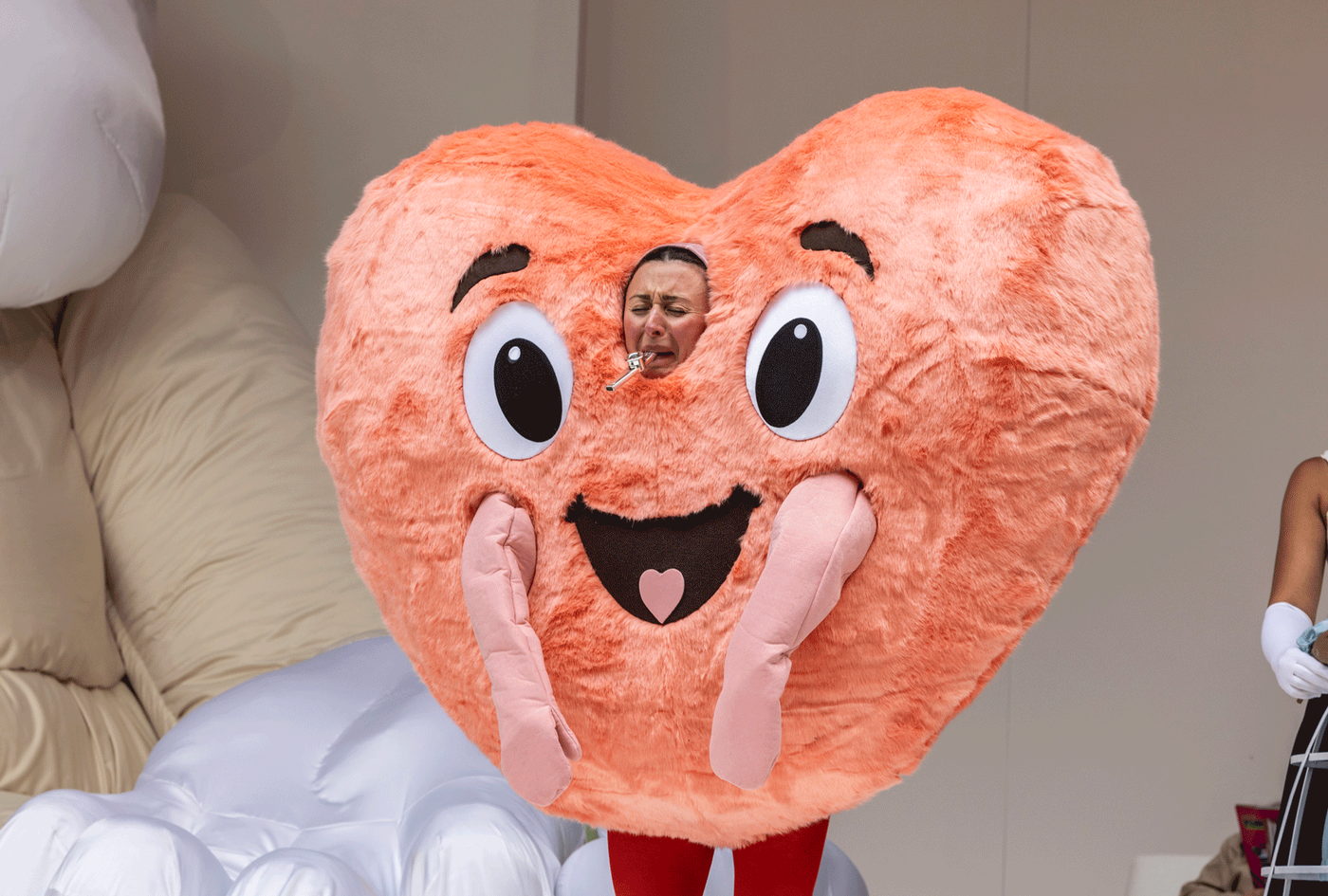 Photo©EllieKurttz_The-Taming-of-the-Shrew_PRO_07June2024_119 Eloise Secker as Grumio wearing a giant heart costume blowing a mini flute. Photography by Ellie Kurttz.