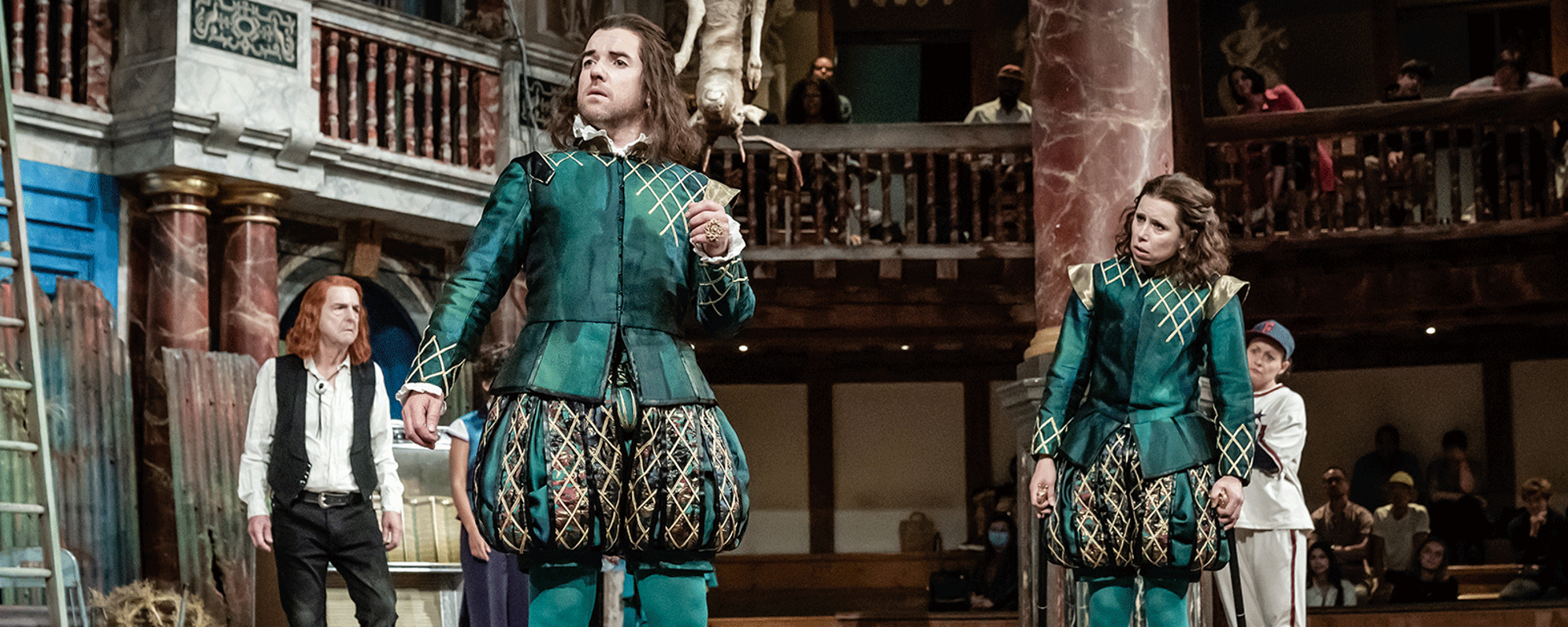 Twelth-Night-Production-Images_0003_Twelfth-Night-Shakespeares-Globe-c-Marc-Brenner-AUD-1704-Ciaran-OBrien-as-S-aspect-ratio-2000-800 A group of people on the stage looking in the same direction